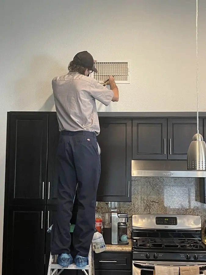Technician inspecting an air vent during HVAC service in Burke